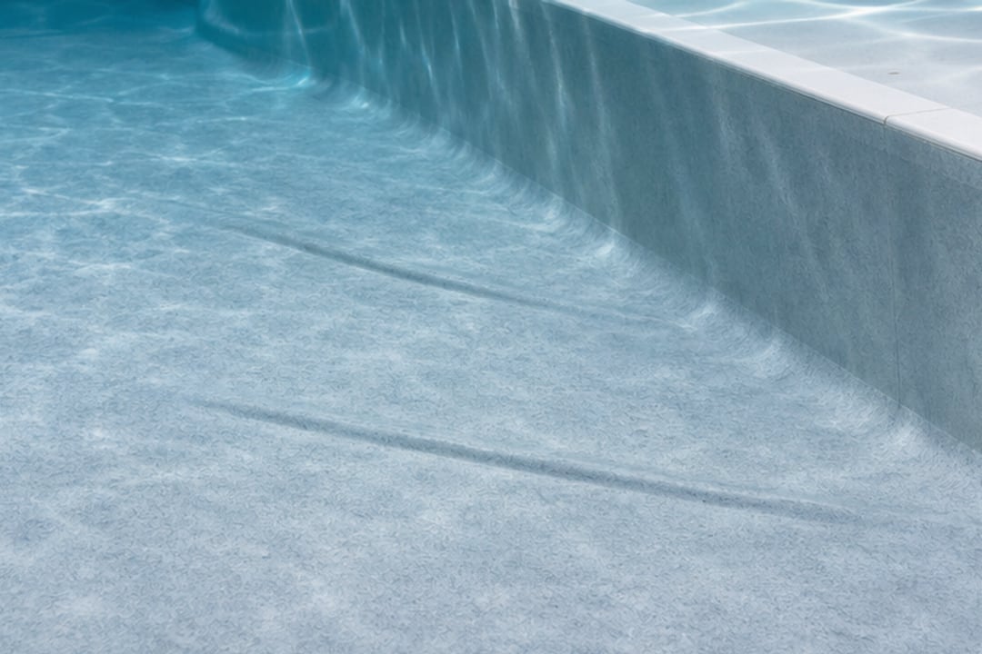 Deux plis discrets visibles sur le fond d’une piscine équipée d’un liner gris bleu